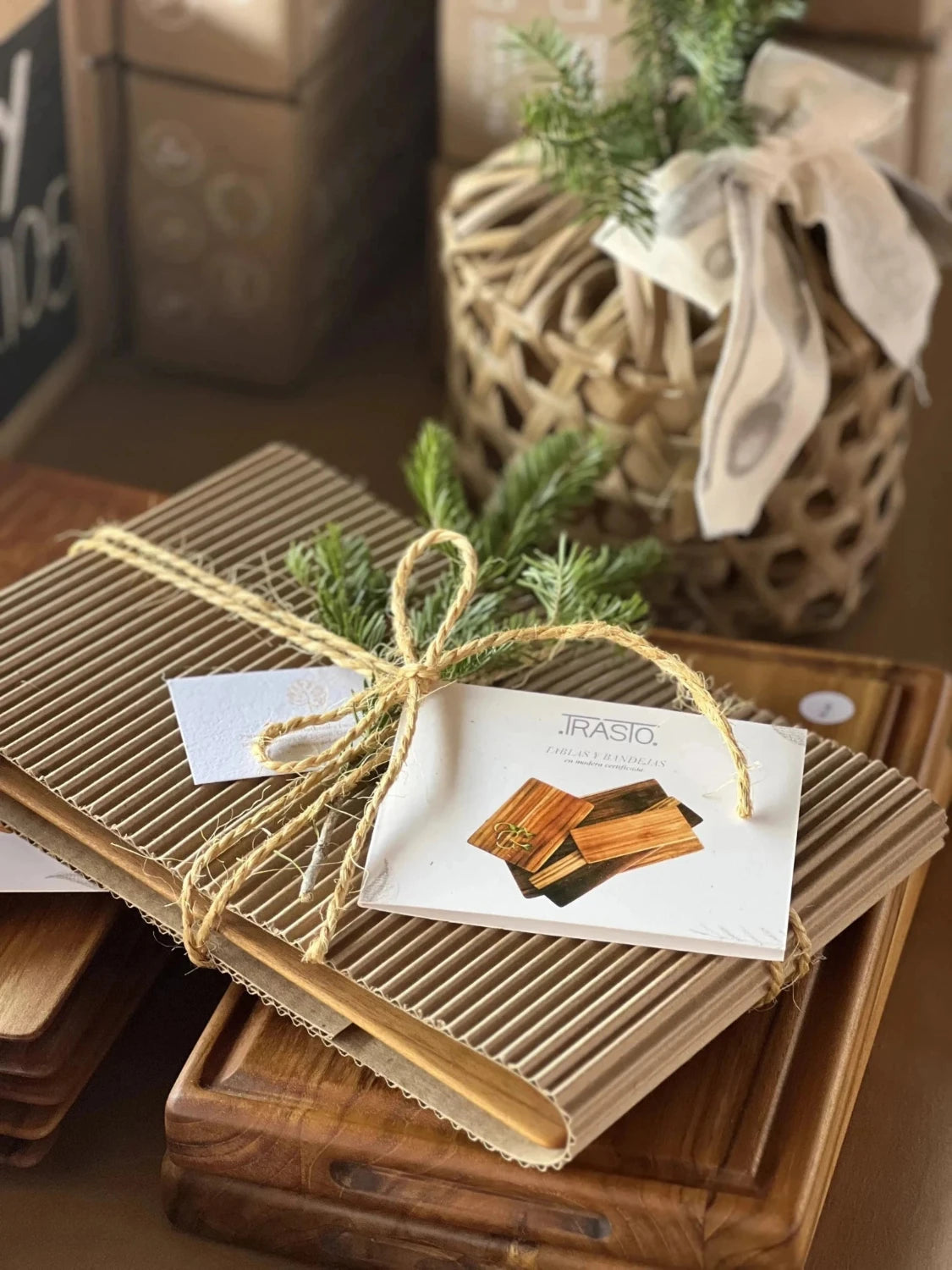 Natural packaging for super lightweight cutting boards, featuring curated cardboard, a natural rope bow, and pine leaves with a label. One board is neatly packed on top of unpacked boards, creating a festive presentation suitable for Christmas.