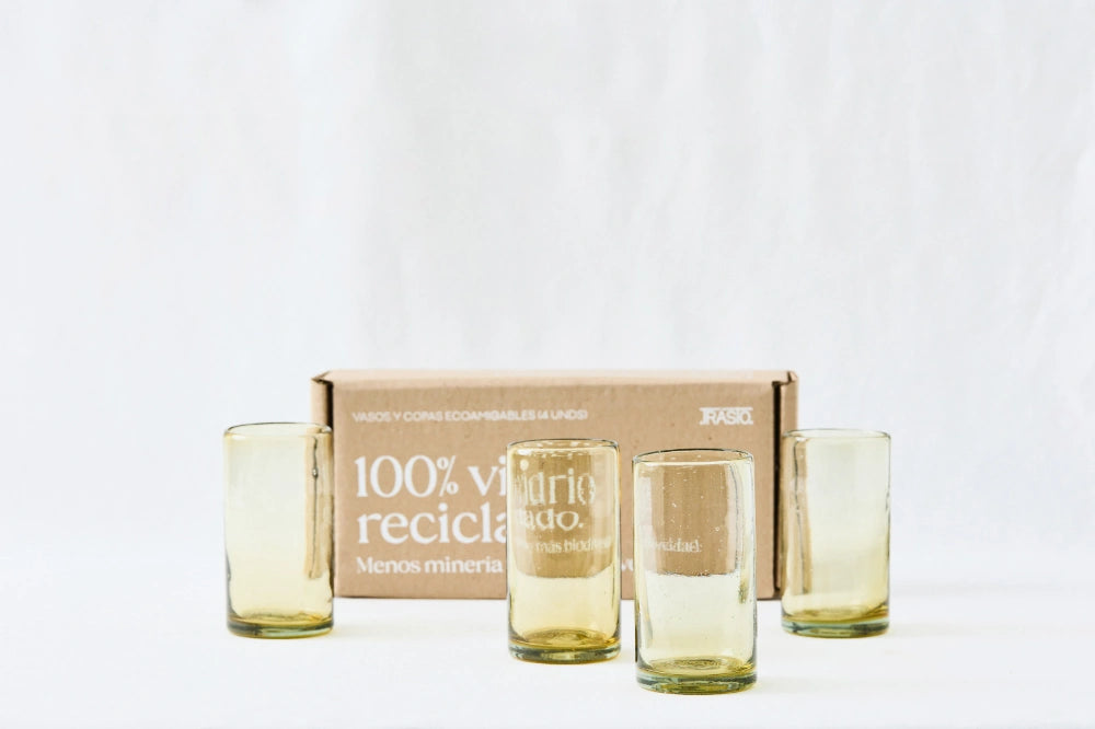 Four yellow amber lightly tinted tall highball glasses, made from 100% recycled glass, shown side by side with packaging on a white background.