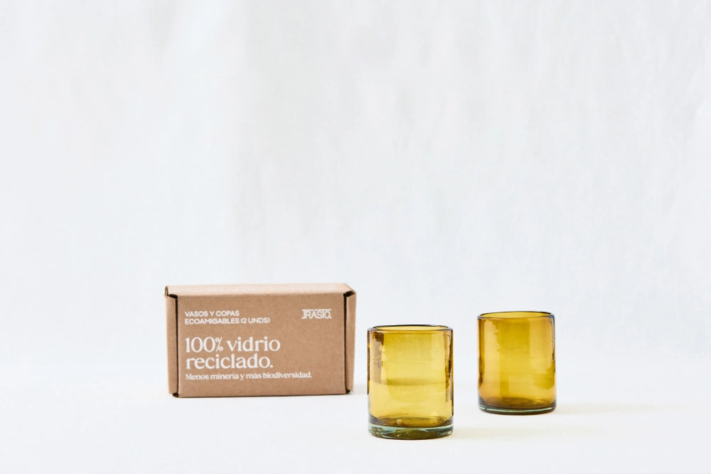 Two amber yellow lightly tinted short glass tumblers, made from 100% recycled glass, standing side by side on a white background.