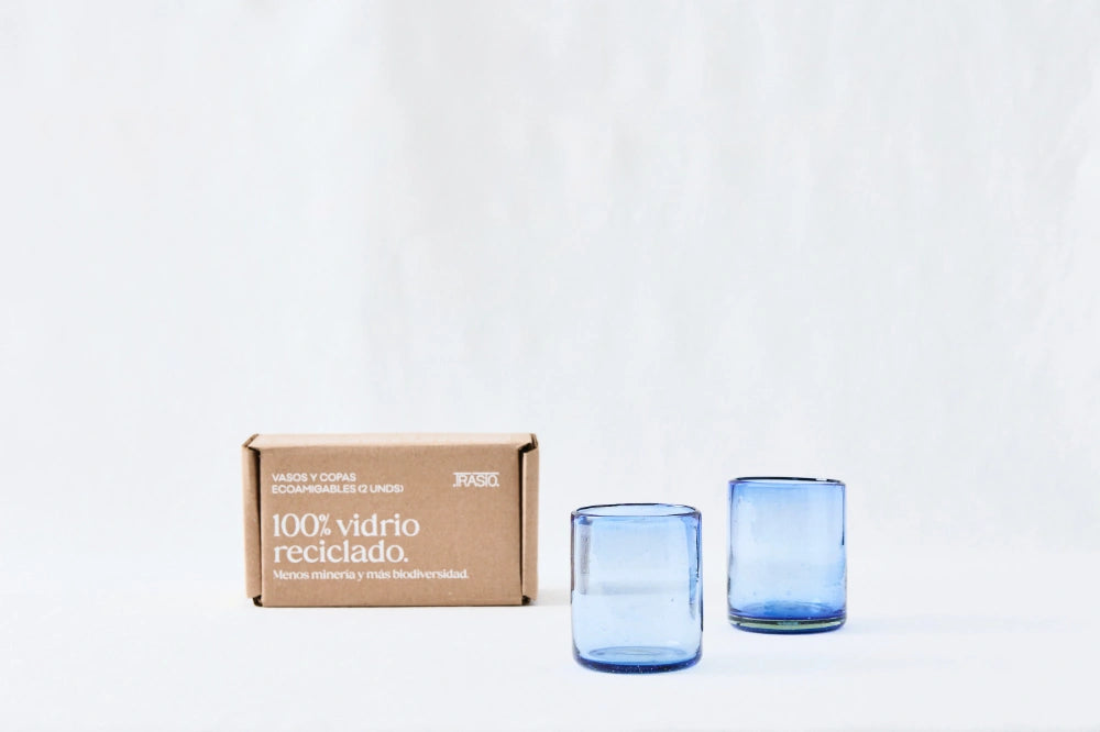 Two blue lightly tinted short glass tumblers, made from 100% recycled glass, standing side by side on a white background.