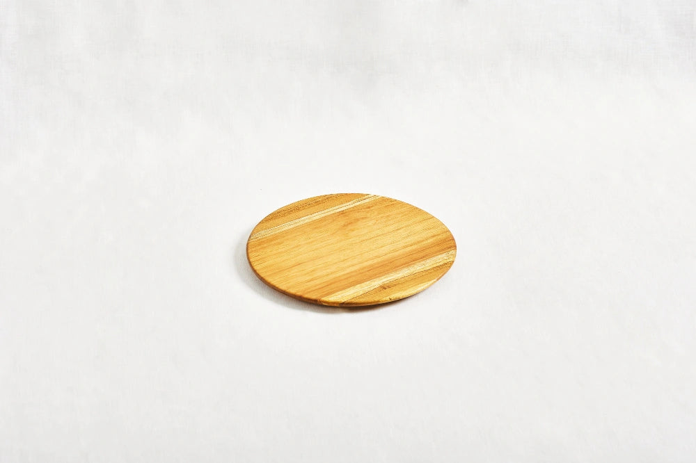 One small round appetizer tray made from 100% certified teak wood, with three cherry tomatoes placed on top, displayed on a white background.