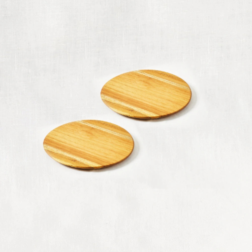 Diagonal view of two small round appetizer trays made from 100% certified teak wood, displayed on a white background.