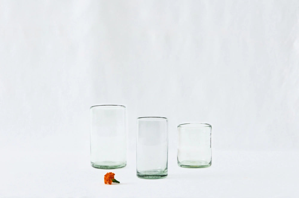 Short, tall, and large everyday clear drinking glasses, made from 100% recycled glass, displayed side by side on a white background.