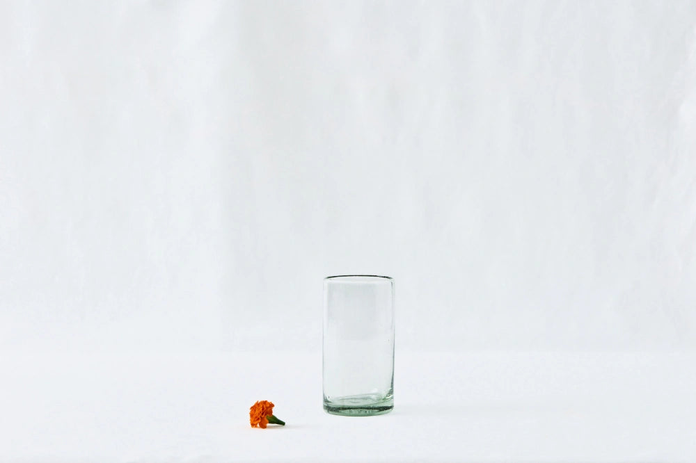 Clear tall highball glass, made from 100% recycled glass, shown from the side on a white background