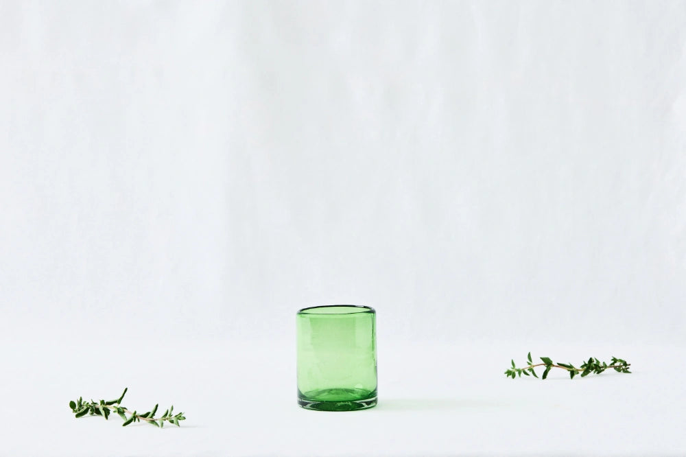 Green lightly tinted short glass tumbler, made from 100% recycled glass, shown from the side on a white background.