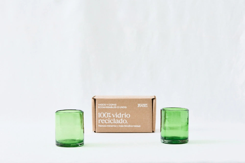 Two green lightly tinted short glass tumblers, made from 100% recycled glass, standing side by side on a white background.