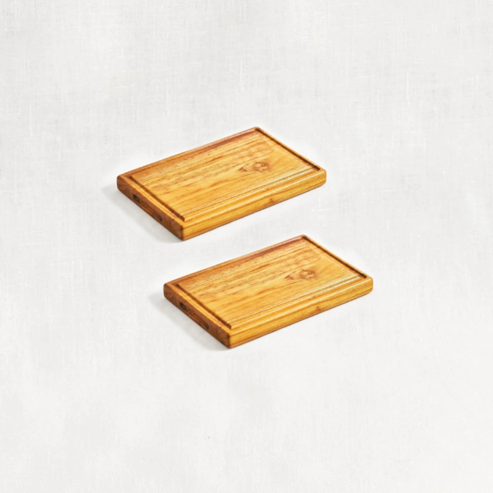 Two small premium reversible teak cutting boards, displayed flat at a diagonal angle on a white background, highlighting their smooth surfaces and dual-use functionality, made from 100% certified teak wood.