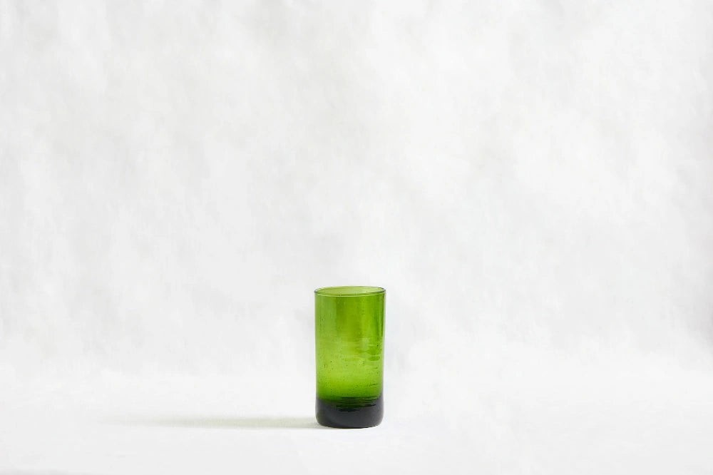 Green deep tinted tall highball glass, made from 100% recycled glass, shown from the side on a white background.