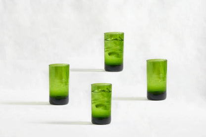 Four green deep tinted tall highball glasses, made from 100% recycled glass, arranged together on a white background.