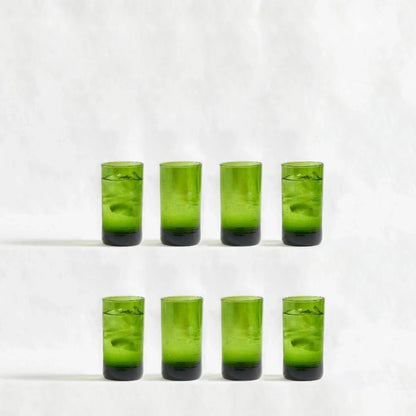 Eight green deep tinted tall highball glasses, made from 100% recycled glass, arranged together on a white background.