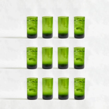 Twelve green deep tinted tall highball glasses, made from 100% recycled glass, arranged together on a white background.