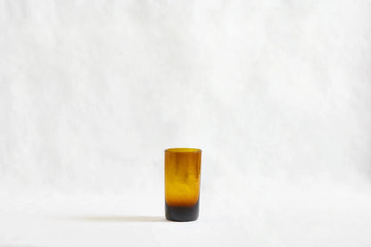 Amber deep tinted tall highball glass, made from 100% recycled glass, shown from the side on a white background.